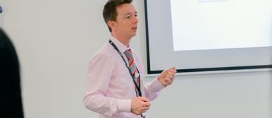 GTG business trainer in front of whiteboard leading a class