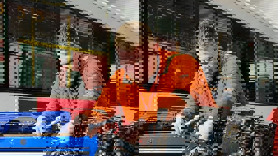 apprentice working on bus engine