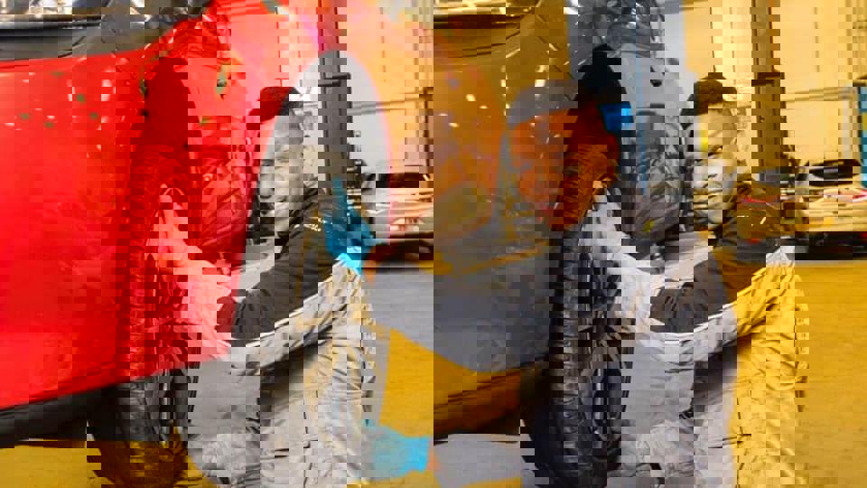 apprentice holding car tyre