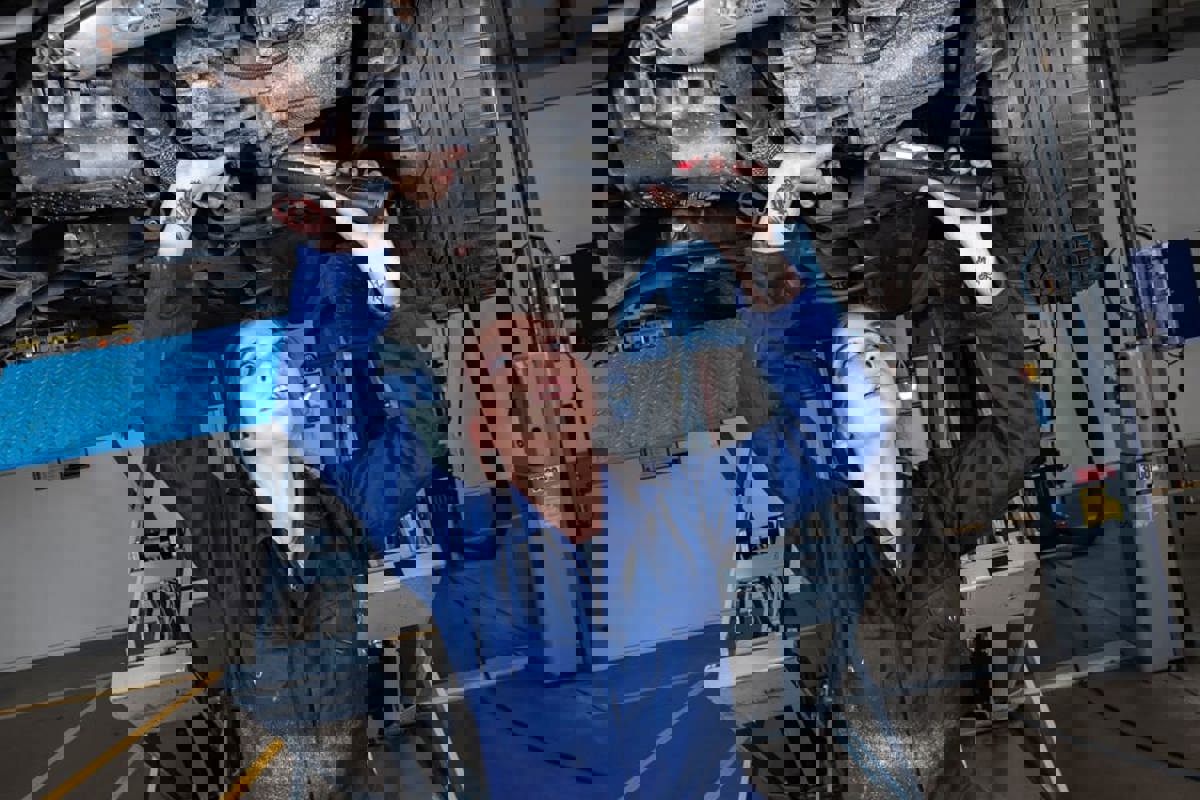 Female apprentice working underneath a car on the ramps