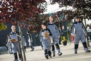 Four apprentices walking in front of GTG building with their certificates