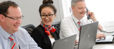 three GTG employees working on laptops smiling